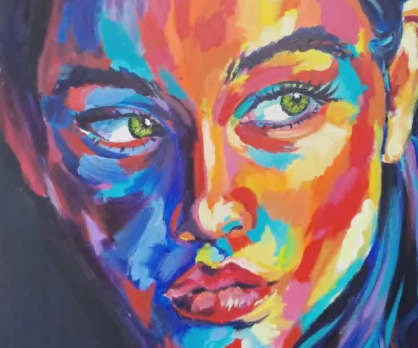 Schilderij van een vrouwelijk gezicht in close-up, weergegeven in levendige, contrasterende kleuren. De huid is opgebouwd uit felle tinten rood, blauw, oranje, geel en paars, waardoor het portret een expressieve, bijna elektrische energie uitstraalt. De groene ogen vormen een scherp contrast met de warme kleurvlakken en lijken de toeschouwer intens aan te kijken. De achtergrond is donker, waardoor de kleuren nog sterker oplichten en het gelaat een aura van kracht en emotie krijgt.