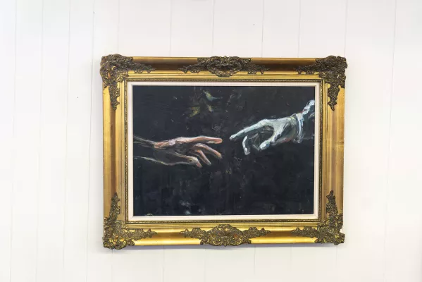 een schilderij van twee handen die naar elkaar uitreiken. De iconografische link met de geboorte man Adam. 
