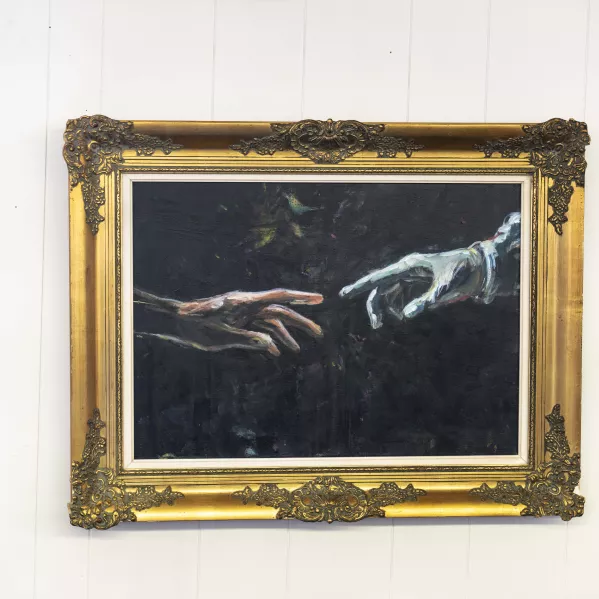 een schilderij van twee handen die naar elkaar uitreiken. De iconografische link met de geboorte man Adam. 
